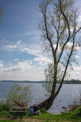 Fototapeta premium A couple of people relax by the lake on a spring afternoon.
