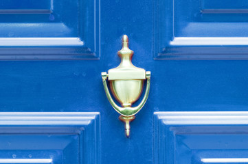 Door knocker. Old antique golden brass knocker on the abstract blue wooden doors for knocking close up