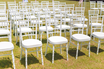 Beautiful arrangement for wedding ceremony event on the natural outdoors lawn park background. Flowers, tables, chairs, elegant romantic decoration details and luxury gathering lifestyle