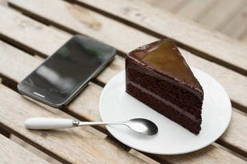 Chocolate cake with mobile phone on table.