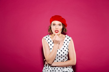 Concentrated ginger woman in dress with finger on chin