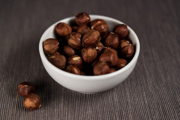 White cup filled with nuts, hazelnuts. View from above.