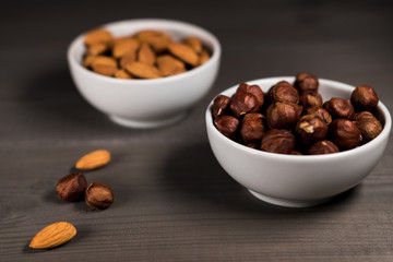 Two white cups filled with nuts, minadal and hazelnuts