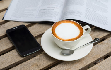 Hot coffee with phone on table.