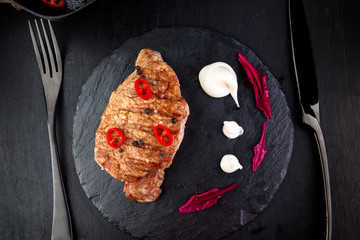 Grilled pork steak on slate plate.