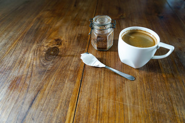  cup of coffee, brown sugar, a spoon. The composition is on a wooden. Stand on a wooden table. Front view with copy space
