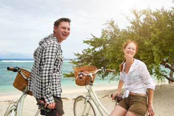 Portrait cheerful young people talking and smile while standing near their old fashioned bicycles on beach.