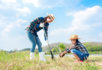 Asian Mom and child girl plant sapling tree in the nature spring for reduce global warming growth feature, reduce global warming and take care nature earth,  blue sky background. .