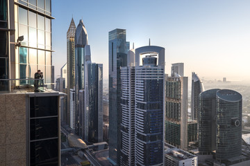 View of a photographer in Dubai International Financial District at sunrise as viewed from a rooftop viewing point. Dubai, UAE.