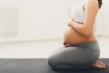 Keuken spatwand met foto Onherkenbare zwangere vrouw die yoga traint in lotushouding © Prostock-studio