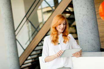 Pretty young red hair woman using digital tablet