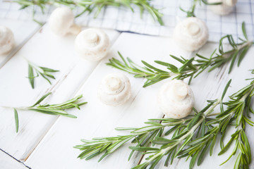 Fototapeta na wymiar Diet, Healthy Food Cooking, Vegetarian Concept. Button mushrooms and rosemary on a white wooden table and plaid napkin, selective focus, close up