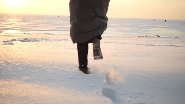 Legs of woman walking on snow with footprints on snowy day