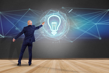 Businessman in front of a wall with bulb lamp idea concept icon on a futuristic interface