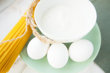 Cooking Homemade Spaghetti with eggs, flour on a blue plate on a white wooden table with blue napkin