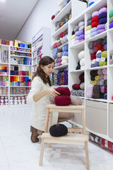 business woman organizing wool yarns at her own enterprise of woollen yarns