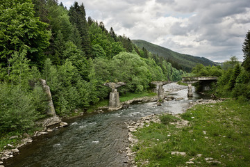 Fototapeta na wymiar Ruined bridge over the Prut River in the Ukrainian Carpathians