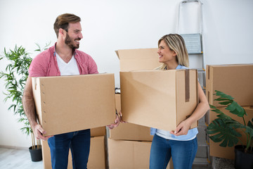 Smiling young couple holding boxes and packing for moving