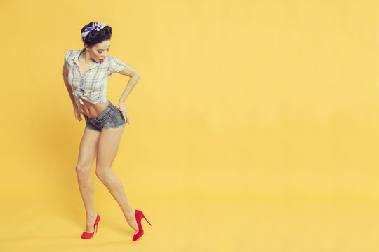 beautiful girl in pin-up style on a yellow background rests on the ass