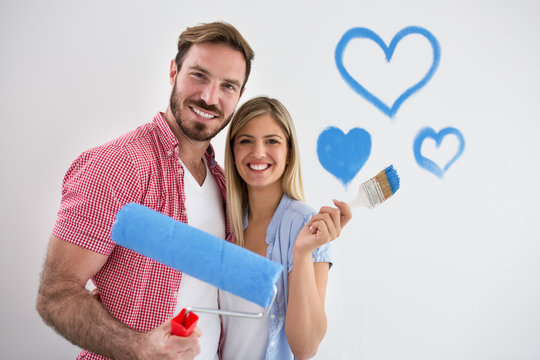 Young happy couple painting new apartment