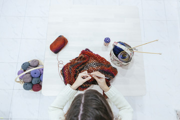 woman knitting a woolen scarf on a white studio
