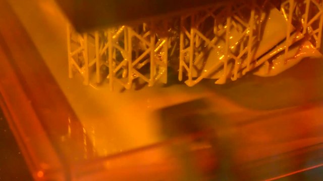 Stereolithography DPL SLA 3d printer create and liquid drips, platform slowly move with liquid close-up. Progressive modern additive technology 3D printing, create scaled model by UV polymerization