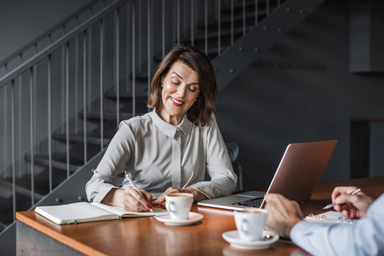 Pretty Caucasian middle-aged businesswoman interviewing a man in coffee shop.