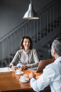 Pretty Caucasian middle-aged businesswoman interviewing a man in coffee shop.