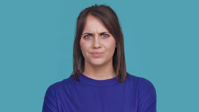 Portrait of confident female feeling disgust listening about something awful expressing rejection and dislike with gesture over blue background. Concept of emotions