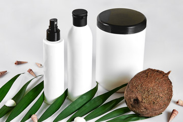 Coconut with jars of coconut oil and cosmetic cream on white background