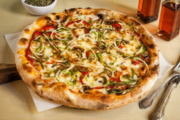 Vegatarian pizza with tomato, bell pepper, onions, mushrooms and mozarella cheese.