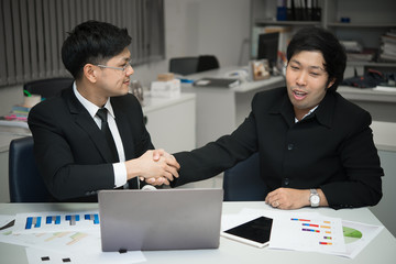 Asian Business people shaking hands, finishing up a meeting,mission complete,Two business people are holding hands to business cooperation in a future,dollar money background