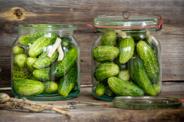 Jars of pickled marinated cucumbers on rustic table