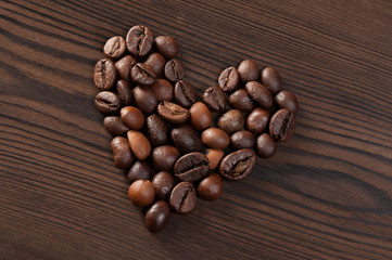 Coffee beans in the shape of heart on a wooden background