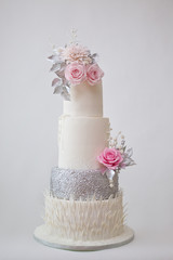 Four tier white, silver and pink wedding cake isolated on white background, winter frozen theme