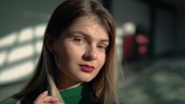 Portait of stylish young woman wears in green blouse looking to camera, indoor slowmotion