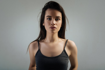 Model. Good-looking serious dark-haired young woman having deep eyes and long hair and staring and wearing a shirt