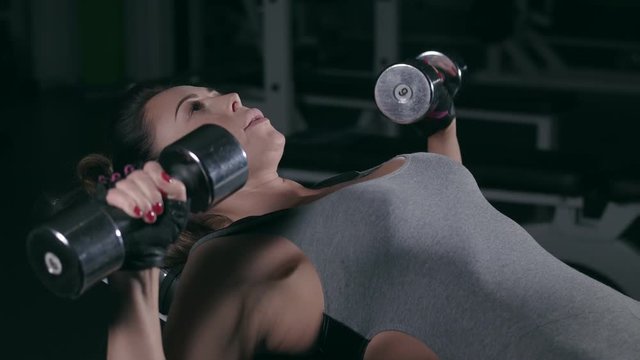 Girl training with dumbbells in the gym