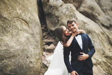 Gorgeous bride, groom kissing and hugging near the cliffs with stunning views
