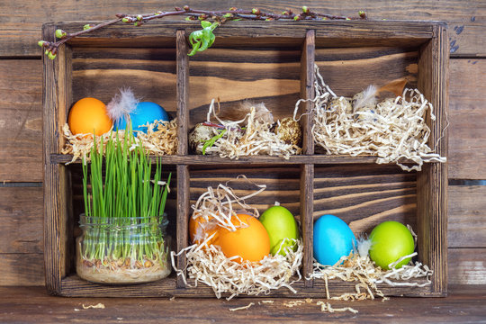 Happy easter holiday concept. Colorful chicken eggs quail eggs germinated wheat in glass jar branch of trees with buds.