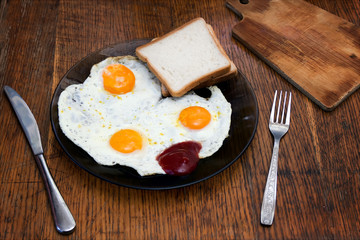 English breakfast, fried eggs with toast on an old textured table