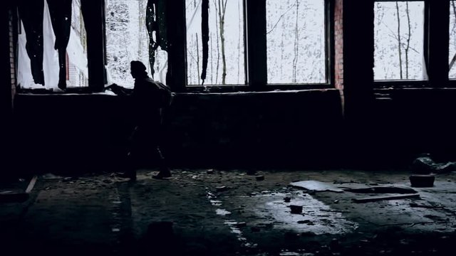 Military with a gun goes to an abandoned building