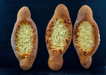 Georgian Khachapuri bread on a black wooden background