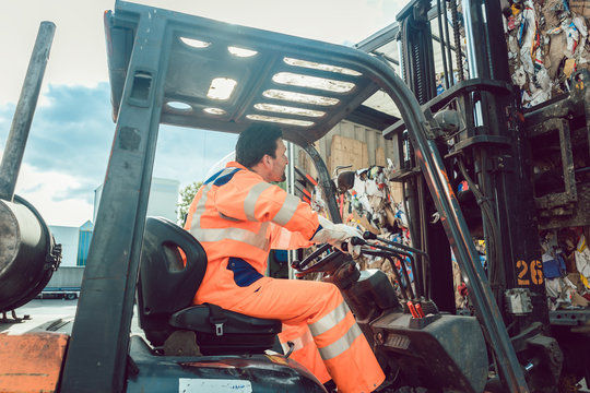 Worker loading separated waste on truck for recycling