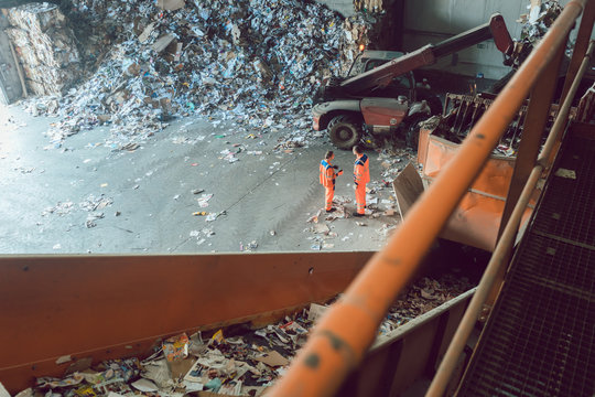 Workers standing at conveyor in recycling facility