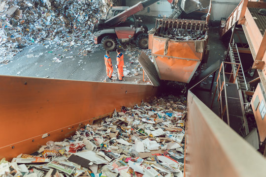Workers standing at conveyor in recycling facility