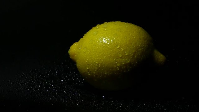 Lemon in droplets of water on a black background. 
