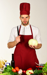 Chef with serious face holds cabbage and knife