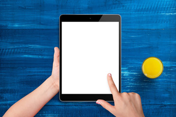 Little girl holding black tablet with empty screen on blue wooden desk while drink juice