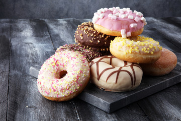 assorted donuts with chocolate frosted, pink glazed and sprinkles donuts. - obrazy, fototapety, plakaty
